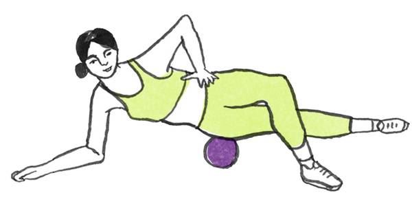 En person ligger på siden og bruker en treningsball under låret for å utføre en øvelse, iført treningstøy og sneakers.