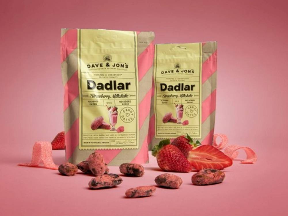 To poser med hundematposer fra Dadlar, omgitt av jordbær og små godterier, mot en rosa bakgrunn.