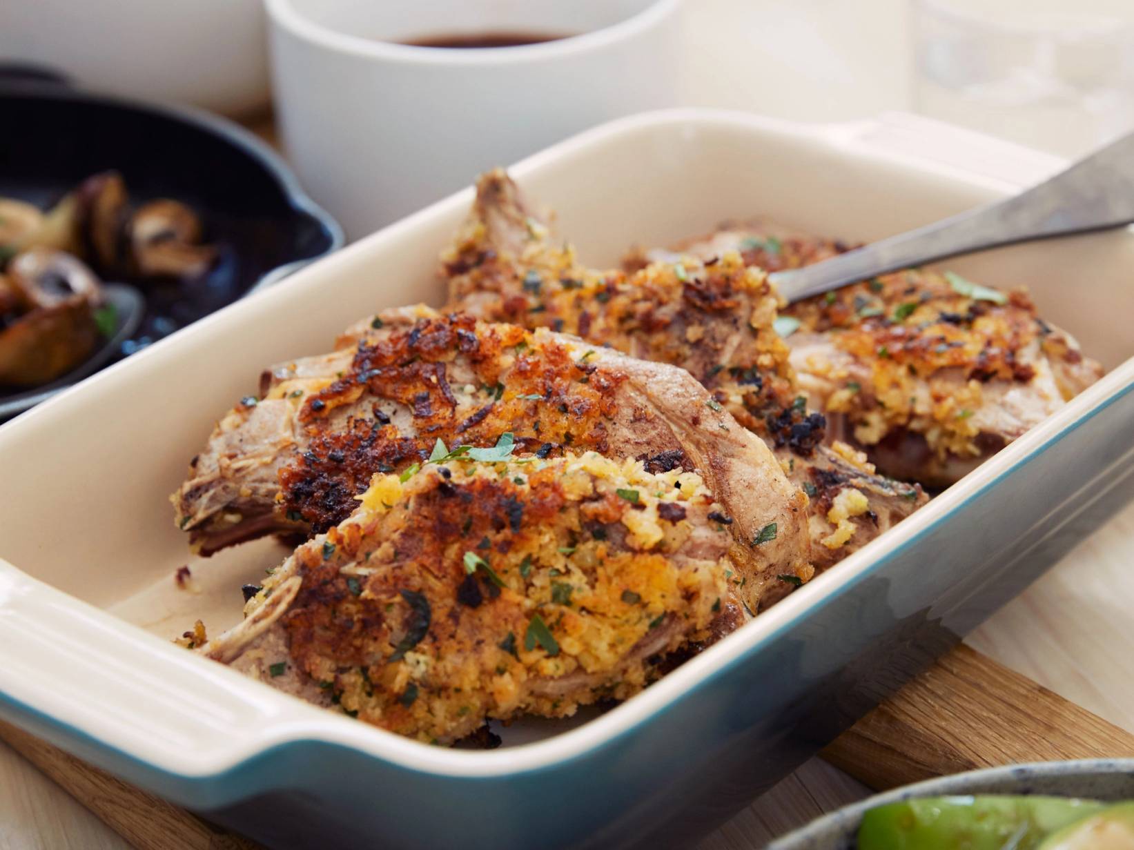 Stekte lammeribbe med sprøtt brød og grønnsaker på et fat, klar til servering.