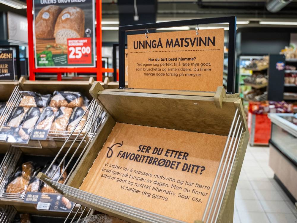 En butikkhylle med en informasjonskasse som har skilt om matvalg og favorittbrød, omgitt av brød og bakervarer.