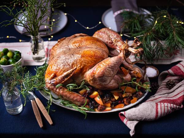 En stekt kalkun på et serveringsfat med grønnsaker rundt, klar til nyttårsmiddag.