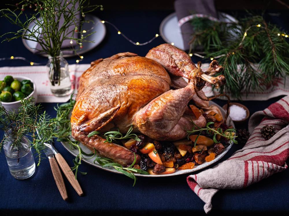 En stekt kalkun på et serveringsfat med grønnsaker rundt, klar til nyttårsmiddag.