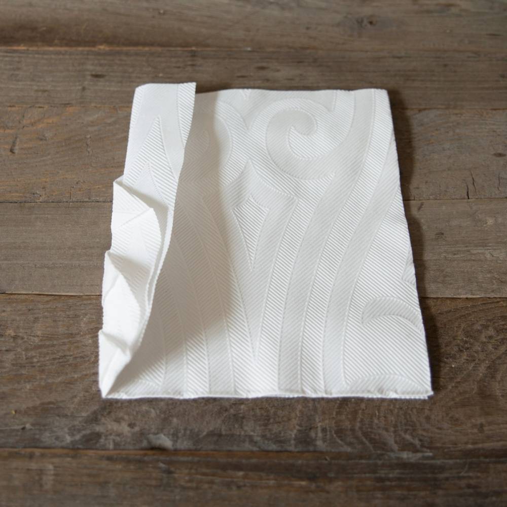 En hvit juleserviett som er brettet og lagt på et trebord