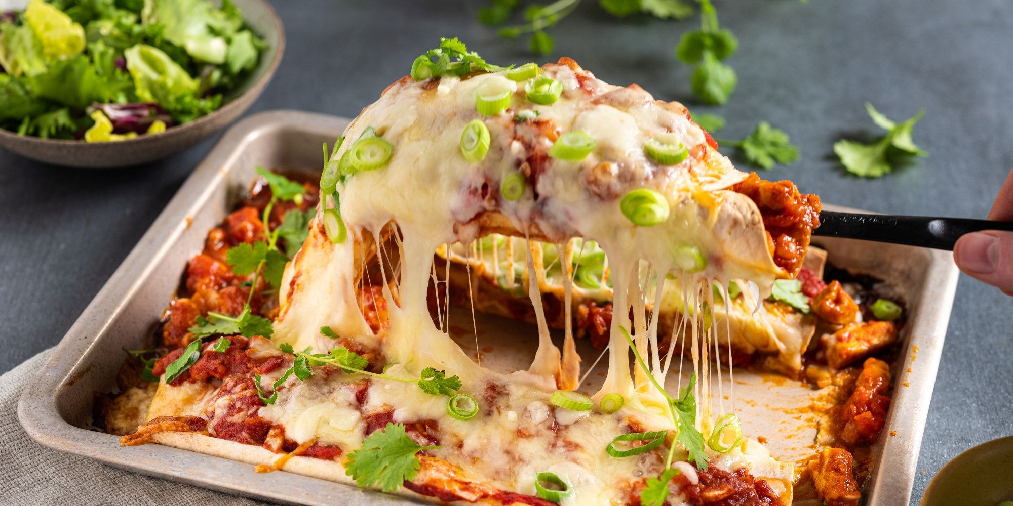 En tallerken med enchiladas fylt med kylling og dekket med ost og grønne erter, klar til å serveres.