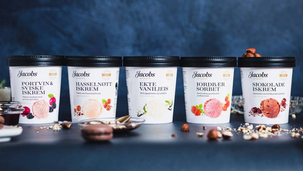 Fem ulike typer iskrem fra Jacobs, med smaker som bringebær, pasjonsfrukt, vanilje, jordbær og sjokolade, på en blå bakgrunn.