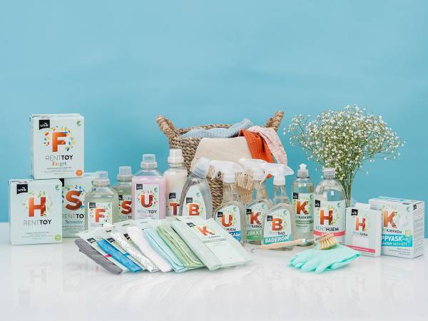 Et utvalg av blå rengjøringsprodukter og hygieneartikler på et bord, med blomster i bakgrunnen.