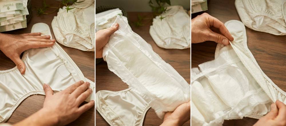 Person viser hvordan man bruker en hybridbleie på et bord med flere bleier og klær rundt seg.