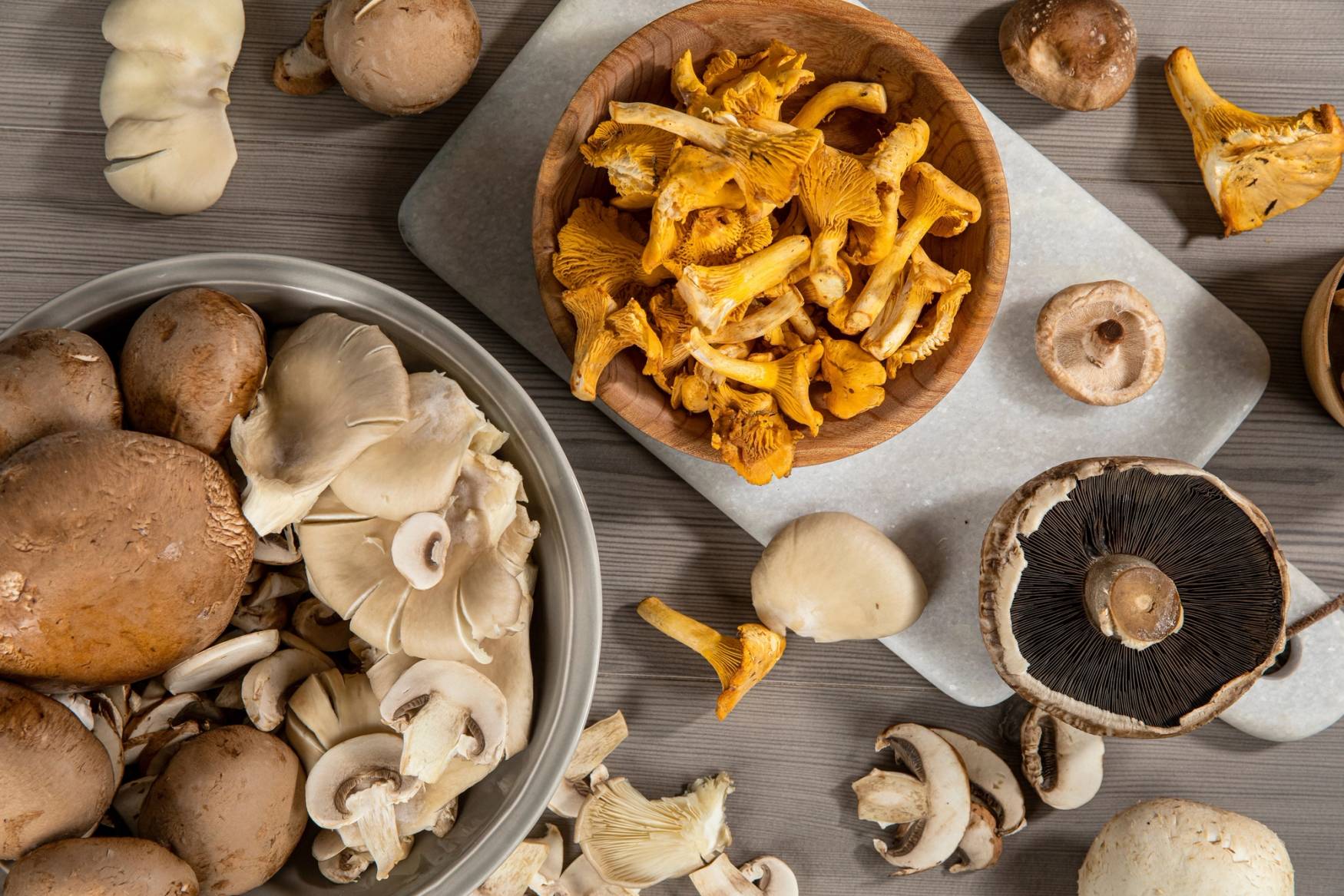 Ulike soppetyper på et bord, inkludert champignon og kantarell, med noen hele og oppskårne soppstykker.