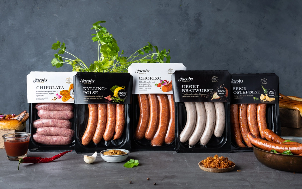 Ulike typer pølser fra Jacobs Utvalgte-serien på en mørk bakgrunn, med tilbehør som sennep, ketchup og krydder ved siden av.