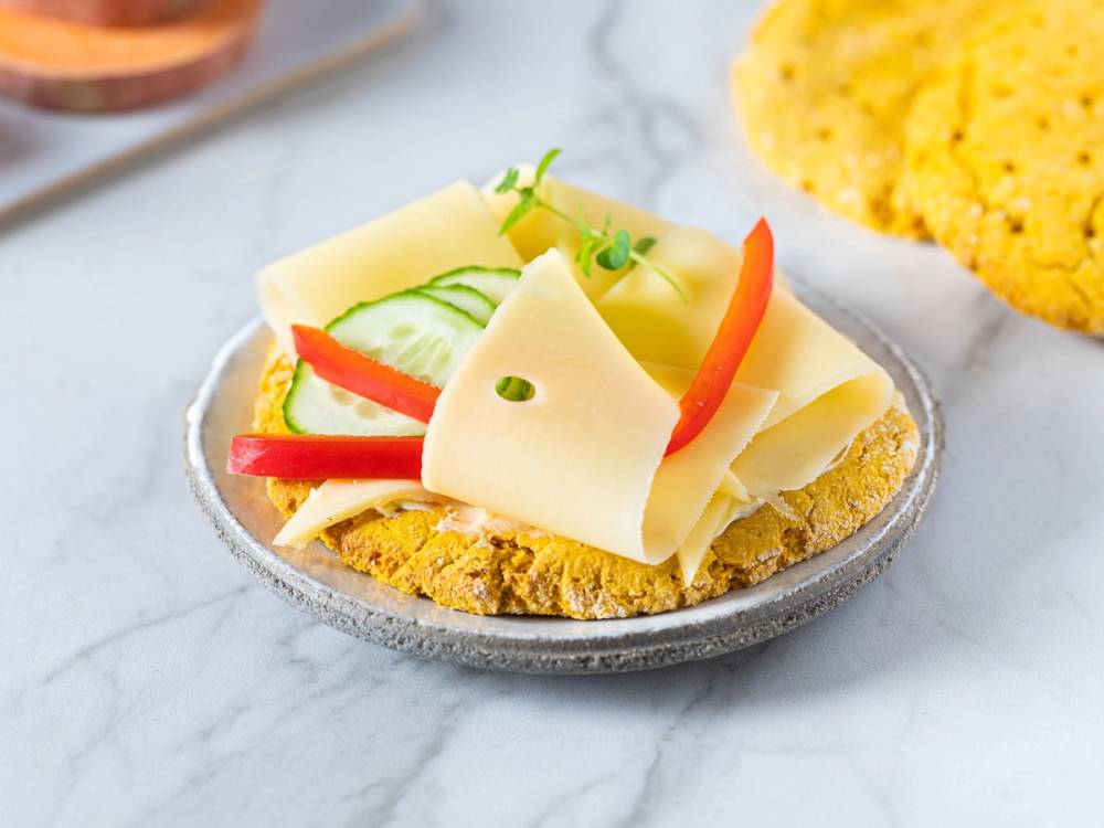 Polarbrod med sotpotet og osteskiver, pyntet med grønne urter, ser ut til å være en enkel snack eller forrett.