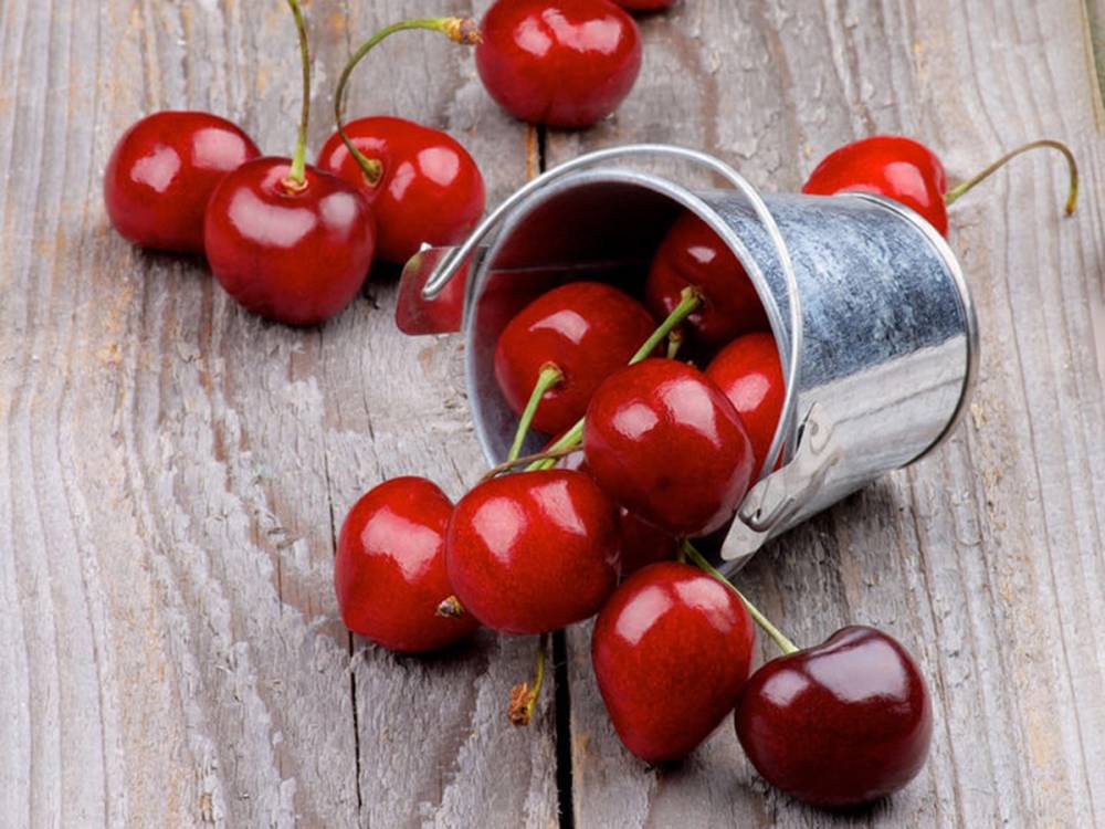 Moreller som har falt ut av en liten metallbøtte på en treoverflate.