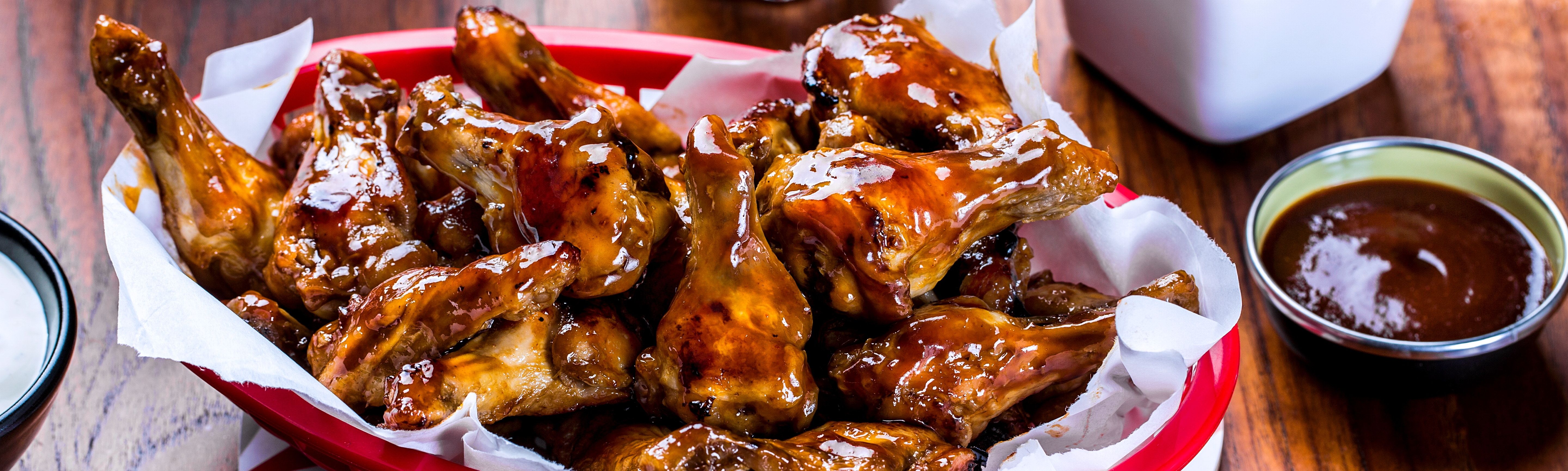 Kyllingvinger med brunt saus på en tallerken, omgitt av små skåler med saus og tilbehør.