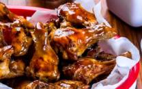 Kyllingvinger med brunt saus på en tallerken, omgitt av små skåler med saus og tilbehør.