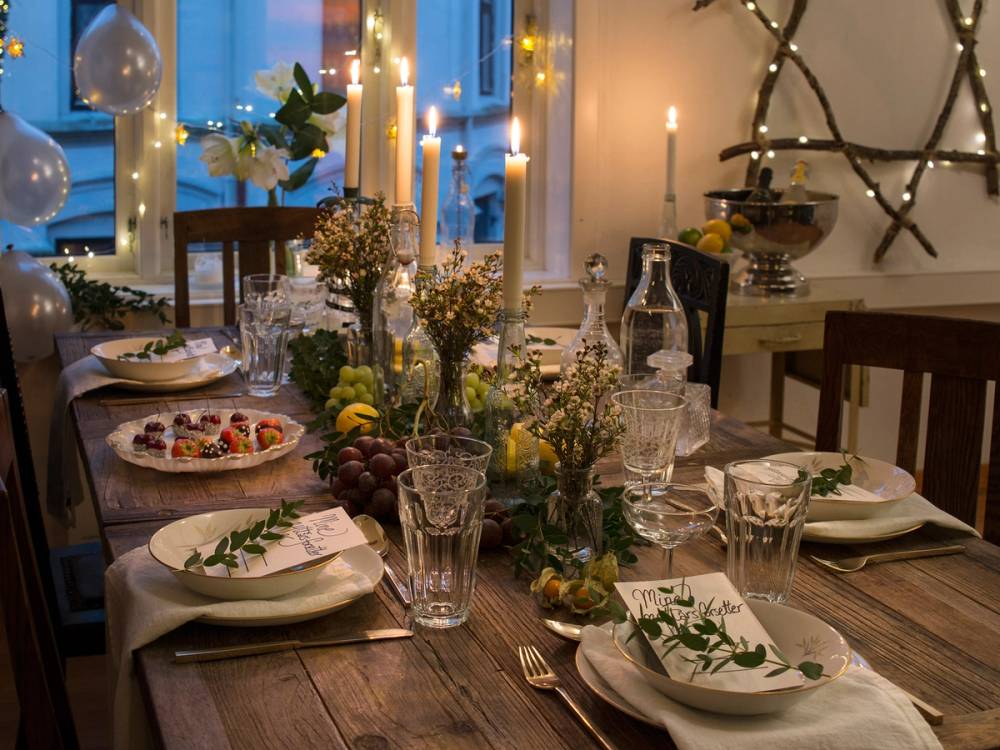 Nyttårsbordet er pyntet med lys, blomster og festlige retter, klar for feiring.