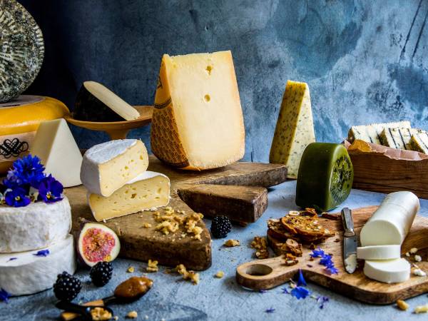 Et utvalg av oster, kjeks og frukt på et bord med en blå bakgrunn.