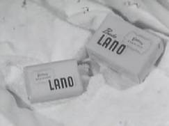 To pakker med LANO-vaskeprodukter ligger på et hvitt stoff, sannsynligvis såpe eller vaskemiddel.