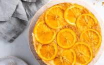 Appelsinkake med skiver av appelsin på toppen, opp ned, på en rund kakebunn.