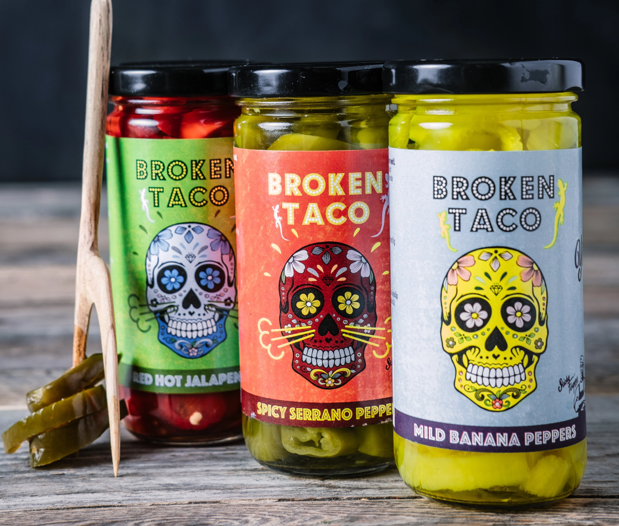 Tre glass med ulike typer peppersaus til taco, med etiketter som viser fargerike skaller og navn på sausene.