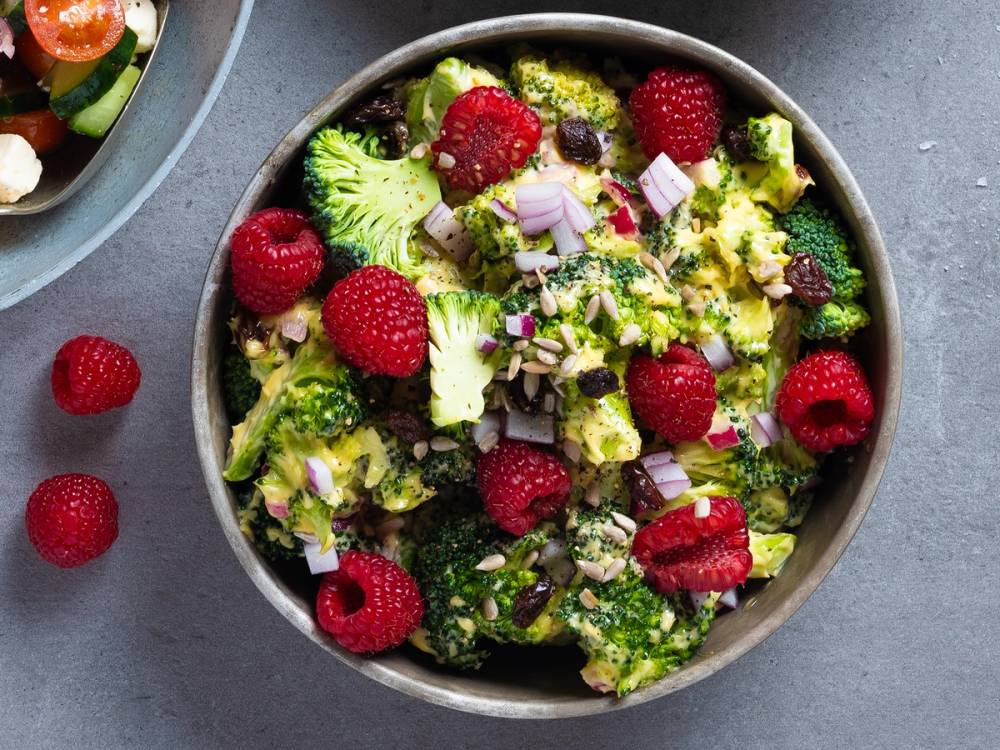 Brokkolisalat med bringebær og hakket rødløk i en bolle