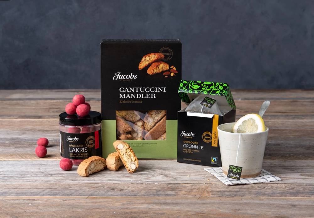 Ulike typer av lakris, cantuccini og mandler på et bord, med pakker og noen løs lakris og mandler rundt.