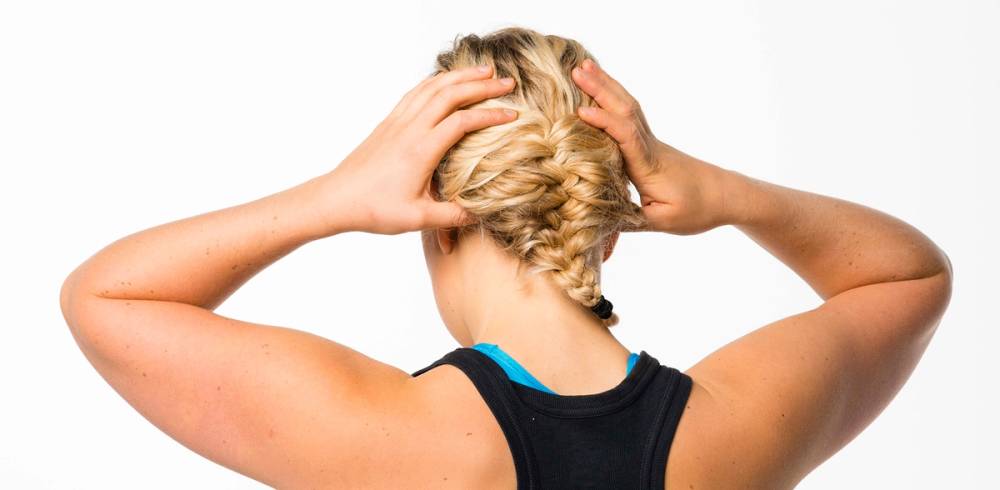 En person med blondt hår som holder hodet med begge hender, muligens under en massasje eller avslapningsøkt.