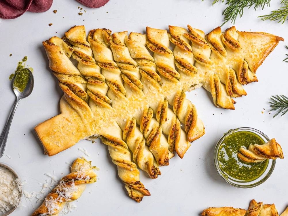 En juleribbe formet som et juletre, pyntet med pesto og omgitt av juledekorasjoner.
