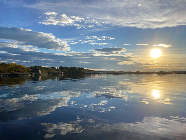 Utsikt over Juvika med vann og speilende himmel under solnedgang eller soloppgang.