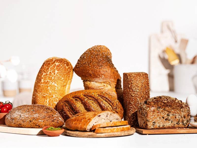 Variert utvalg av brød med lys bakgrunn, inkludert baguette, rundstykker og brødskiver