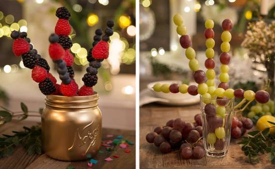 Fruktspyd med ulike bær og frukt, satt opp i glass og en liten gullfarget krukke, brukt til nyttårsfest.