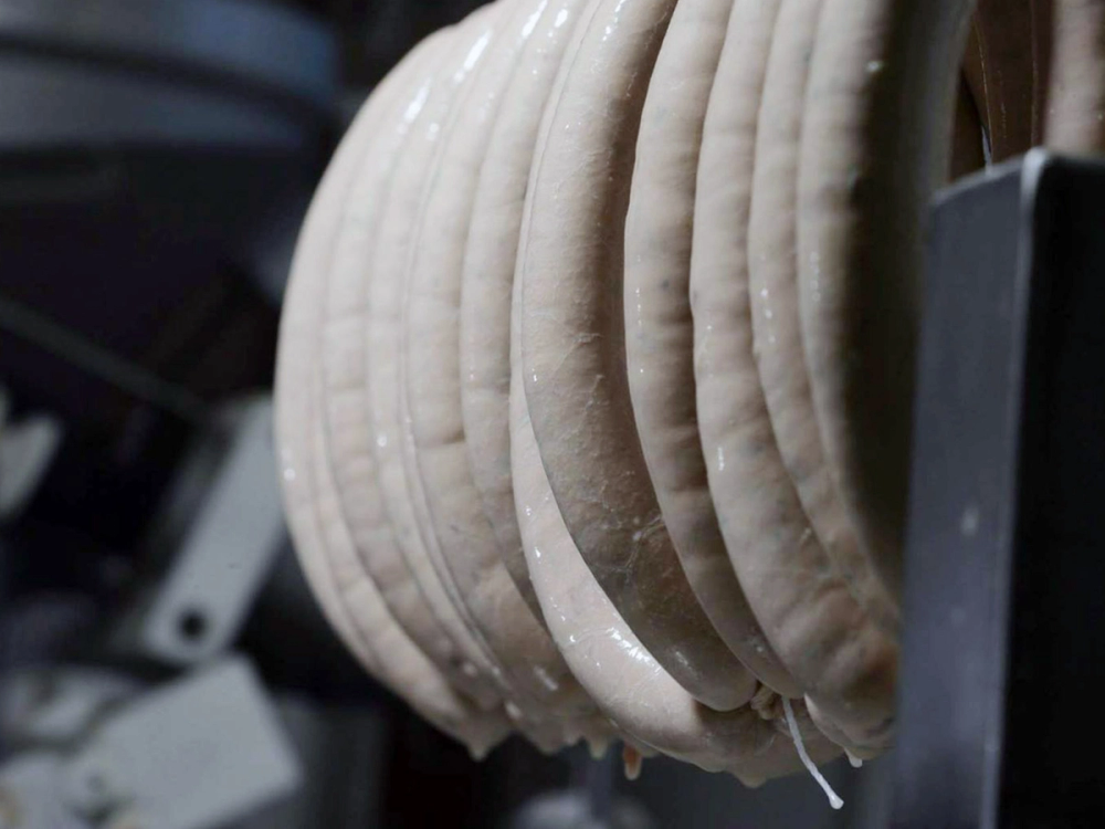 Nærbilde av flere hvite, runde gjenstander som henger i en krok, muligens av tre eller plast, med en mørk bakgrunn.