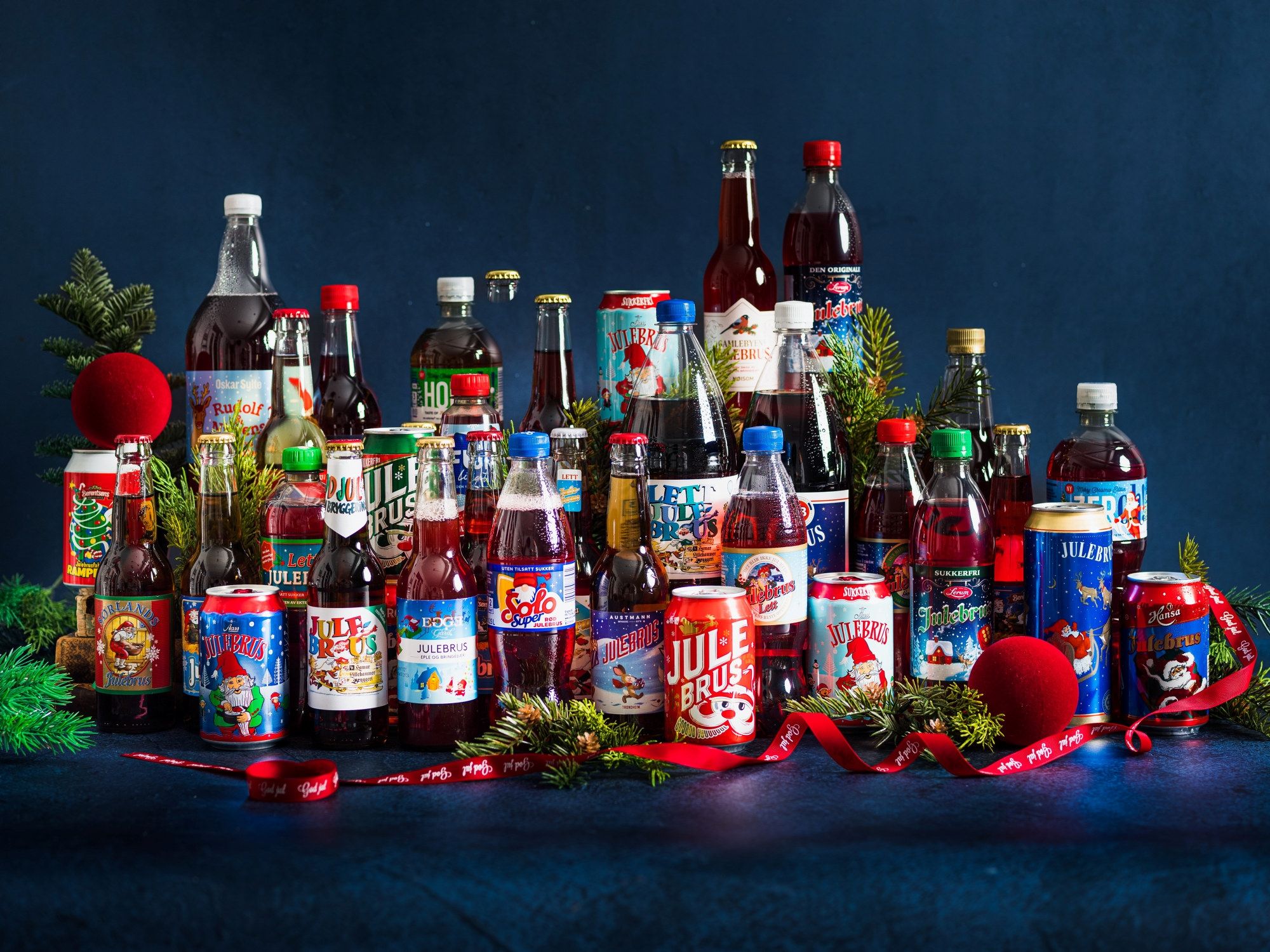 Et utvalg av julebrusflasker og julepynt på en mørk bakgrunn.