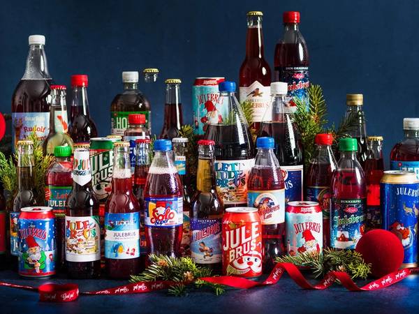 Et utvalg av julebrusflasker og julepynt på en mørk bakgrunn.