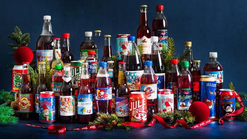 Et utvalg av julebrusflasker og julepynt på en mørk bakgrunn.