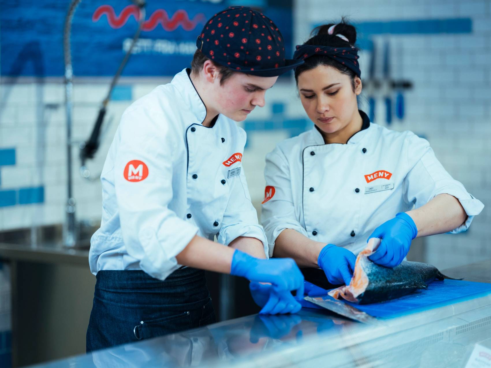 To MENY-ansatte fileterer fersk fisk i fiskedisken.