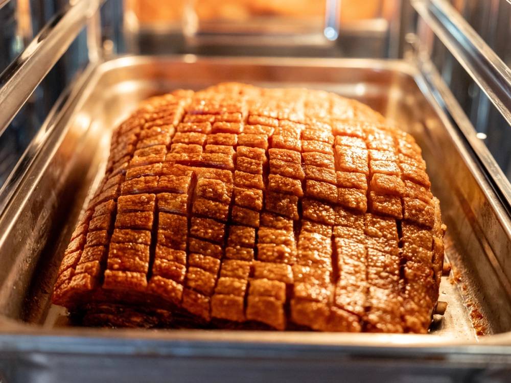 Et stort stykke brunt, skåret kjøtt eller kake i en metallform, klar til servering eller oppvarming.