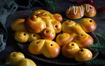 Lussekatter og julekaker på et fat med grønne grener rundt, klar til jul.