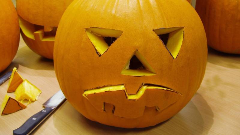 En uthult gresskar med ansiktsuttrykk og lys inni, klar til Halloween, plassert på et bord.