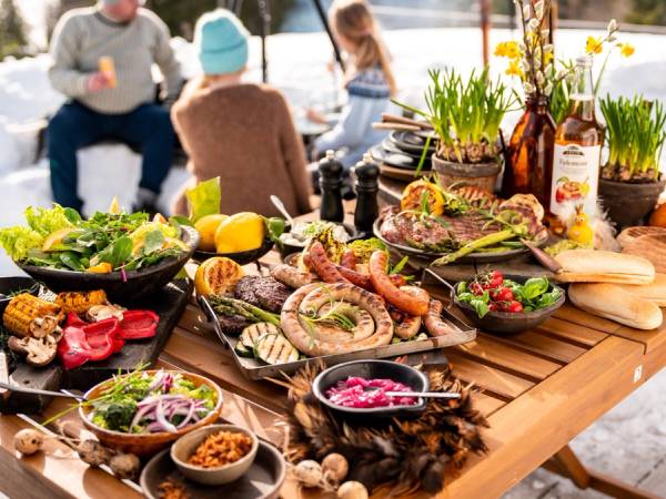 Et bord med et godt utvalg gourmetpølser og tilbehør på en utendørs grilling.