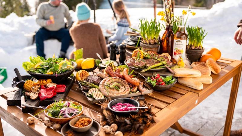 Et bord med et godt utvalg gourmetpølser og tilbehør på en utendørs grilling.