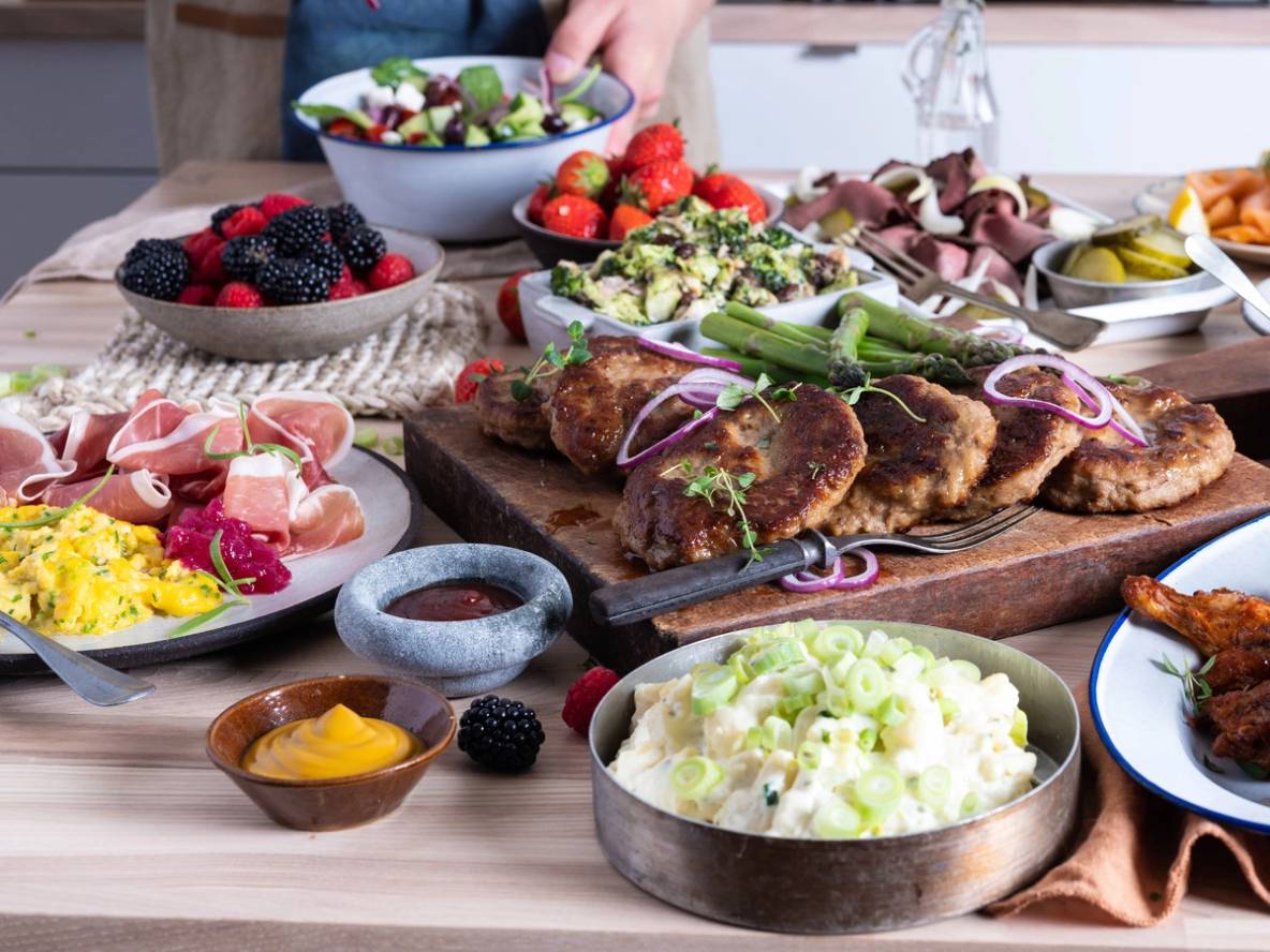 Et koldtbord med ulike typer pålegg, salater og frukt, arrangert på et bord.