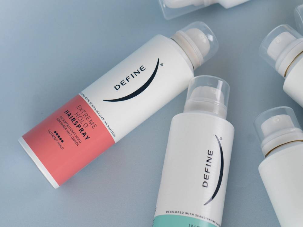 To sprayflasker med hudpleieprodukter fra merket Define ligger på en lys bakgrunn.
