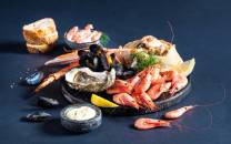 Et utvalg av skalldyr som reker, blåskjell og krabbe på en tallerken med sitron og dipp, klar for helgekos.