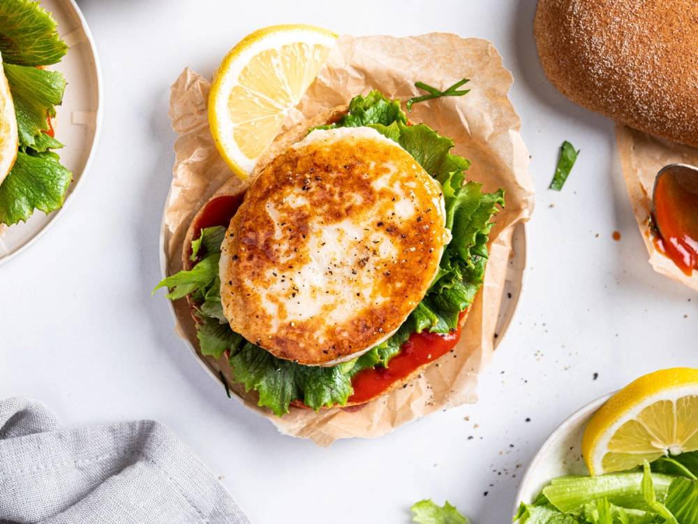 Fiskekake med salat, sitron og brød på en tallerken.