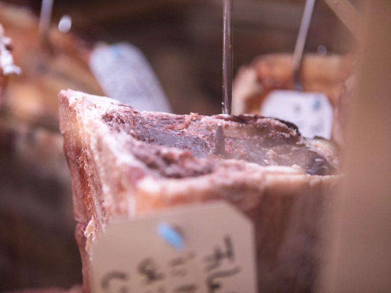 Et stykke tørket kjøtt med en mørk, sprø overflate og en tydelig tekstur, plassert i en butikk eller på et marked.