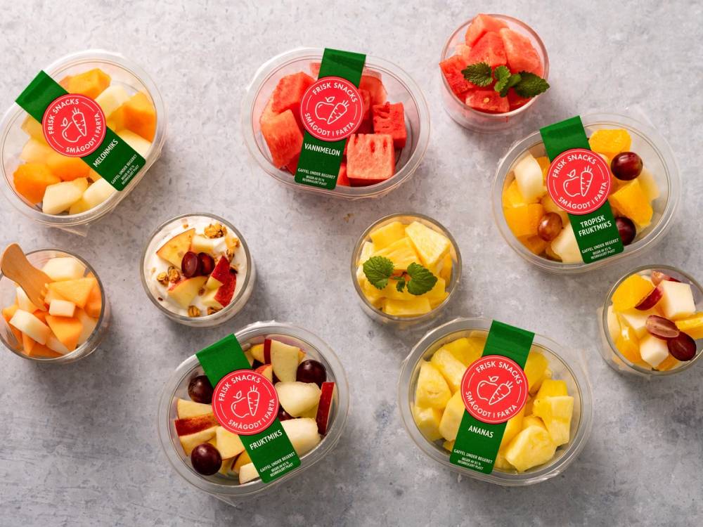 Syv små fruktbeger med ulike typer frukt og bær, pyntet med mynteblader, på en lys bakgrunn.