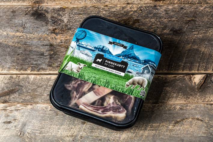 En matboks med julemotiver og bilder av dyr, plassert på et treverk, sannsynligvis til jul, basert på filnavnet meny-jul-8706.jpg.