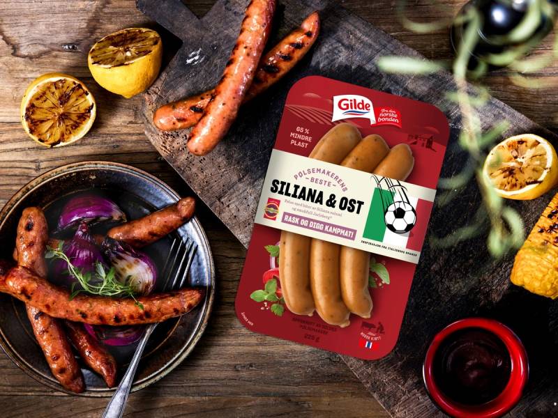 Pakke med Siliana & Ost pølser omgitt av grillede grønnsaker og lime på en treplate.