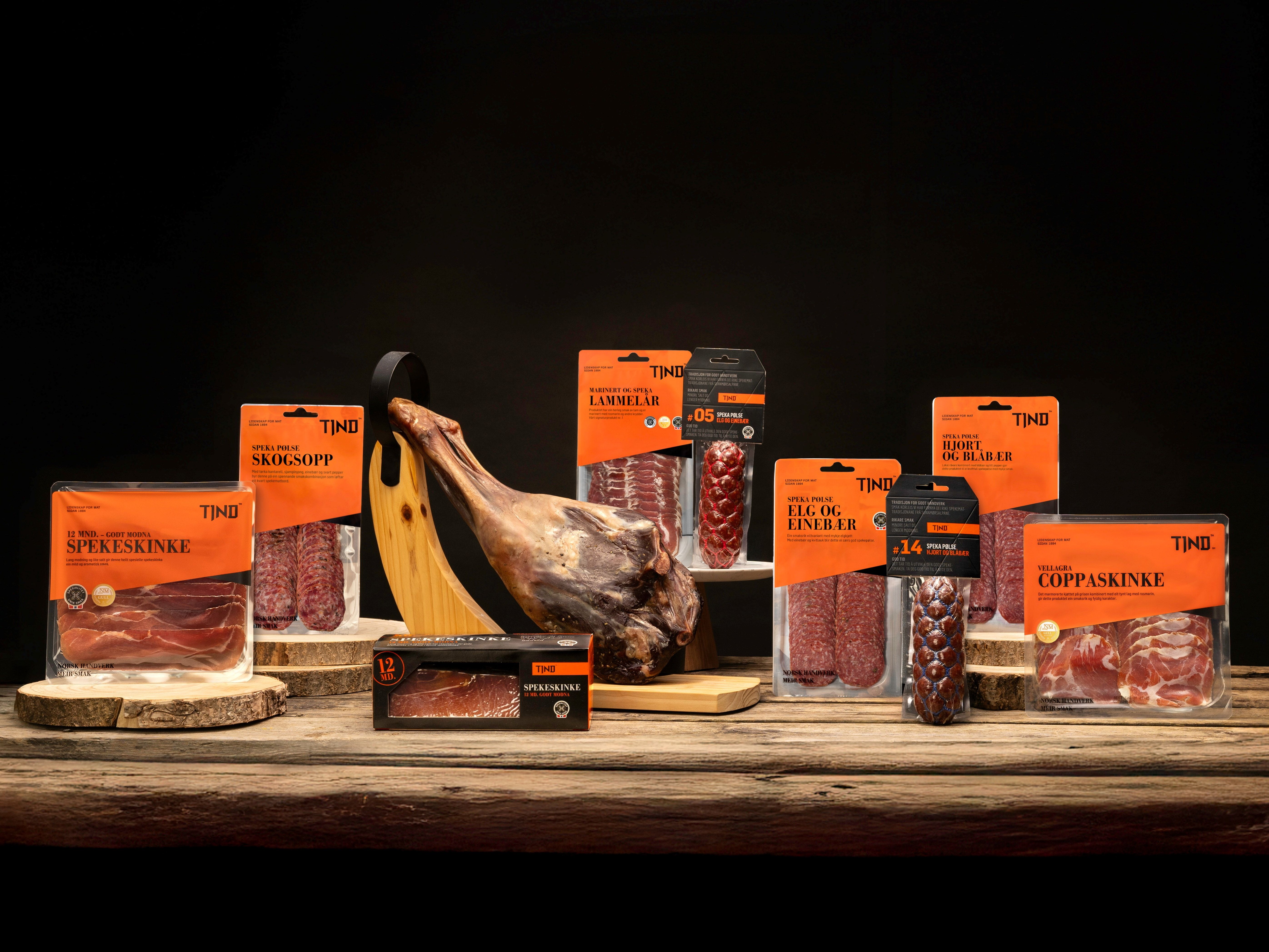 Ulike typer kjøtt og en banan på en treplate, med flere pakker med kjøtt rundt, mot en mørk bakgrunn.