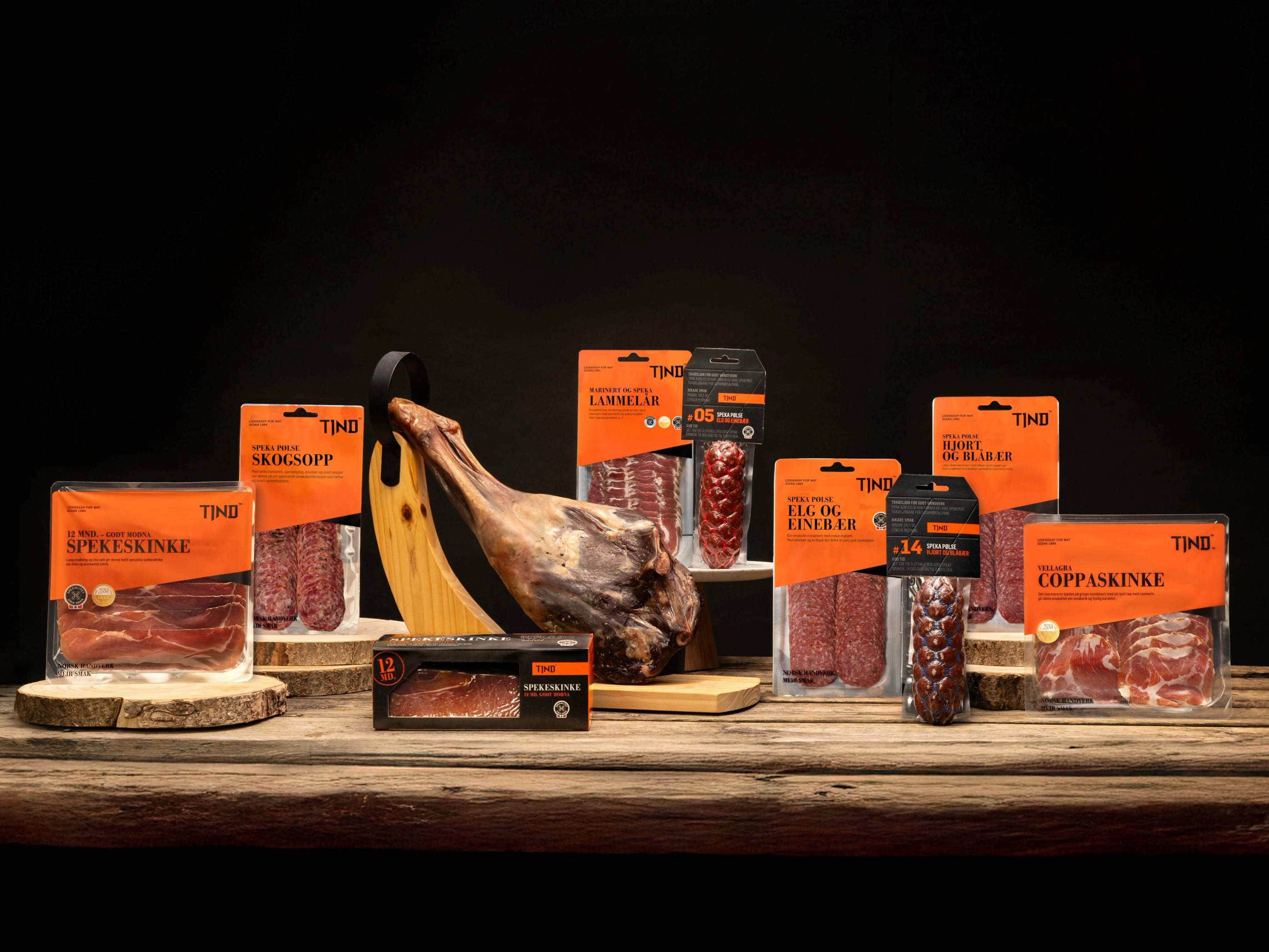 Ulike typer kjøtt og en banan på en treplate, med flere pakker med kjøtt rundt, mot en mørk bakgrunn.