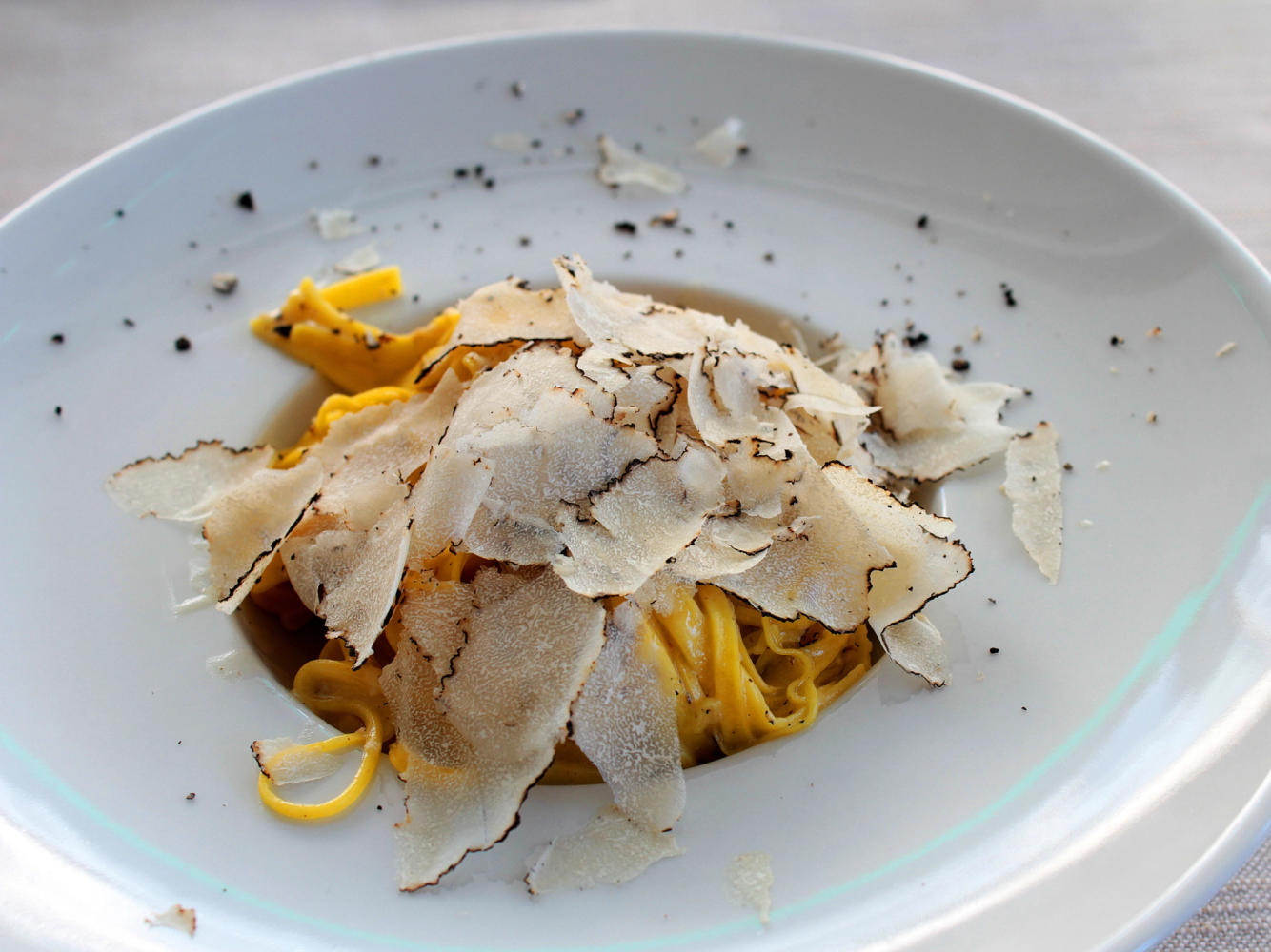 Pasta med trøffelskjell og tynne skiver av trøffel på en hvit tallerken